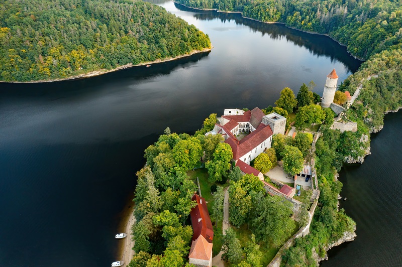 Вид сверху на замок Звиков с традиционными красными крышами, рекой и лесом в Чехии