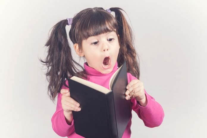 Little girl reacts while reading a book